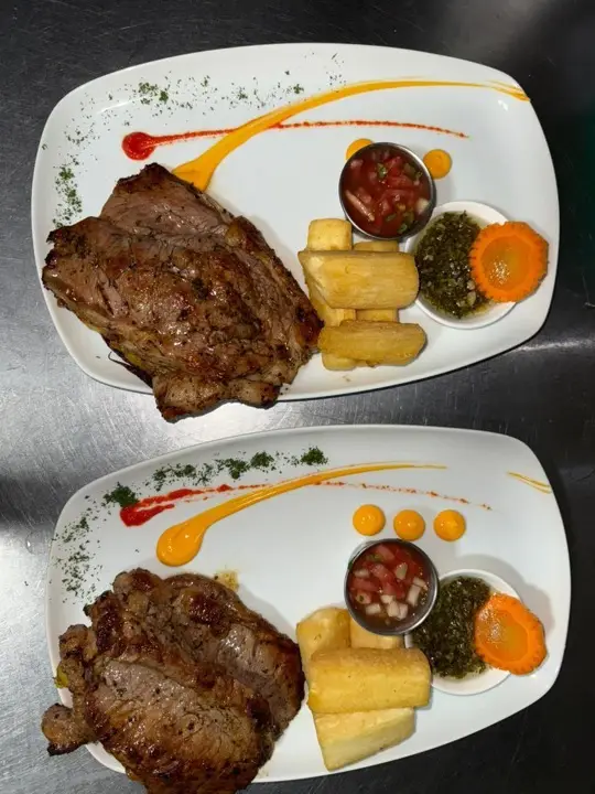 Dos platos de carne a la parrilla con yuca